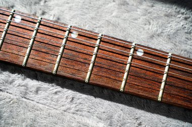 Elektro gitar, çelik teller ve gül ağacından yapılma pervazların yakın çekimi.