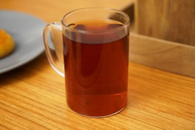 Hassas bir çam fincanının içindeki siyah Türk çayı ahşap masanın üzerinde duruyor. Türkiye 'de bütün gün siyah çay içiliyor                