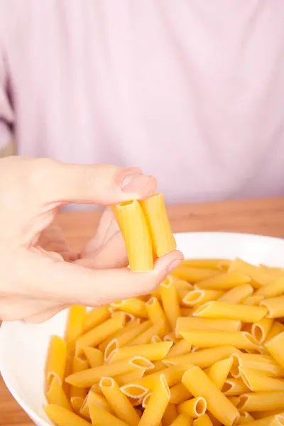 stock image Uncooked raw healthy and delicious pasta macaroni held by a Caucasian man in porcelain plate on wooden table