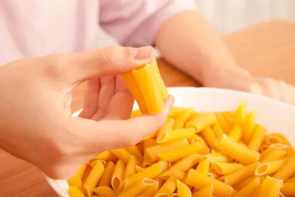 stock image Uncooked raw healthy and delicious pasta macaroni held by a Caucasian man in porcelain plate on wooden table