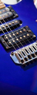Elektro gitar köprüsü, teller ve pikap, ahşap boya mavisi, telli müzik aleti ile gitar pikapının detaylı görüntüsü.