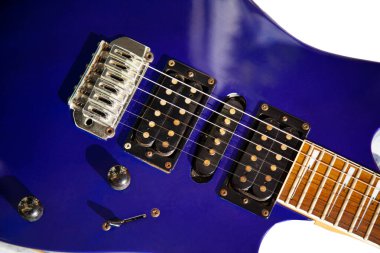 Elektro gitar köprüsü, teller ve pikap, ahşap boya mavisi, telli müzik aleti ile gitar pikapının detaylı görüntüsü.
