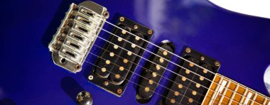 Elektro gitar köprüsü, teller ve pikap, ahşap boya mavisi, telli müzik aleti ile gitar pikapının detaylı görüntüsü.