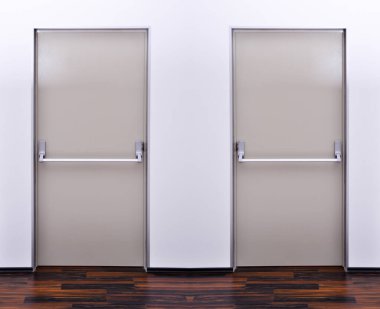 Acil çıkış iki gri kapı. Acil çıkış kapısının mandalı ve turuncu kapı kolu kapalı. Panik çıkışı için parmaklıkları itin.