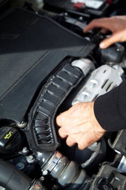 Beyaz bir araba tamircisinin elleri, arabanın motor bölmesinde genel bir kontrol yapılır. Araba bakım ve onarım işleri