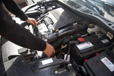 Beyaz bir araba tamircisinin elleri, arabanın motor bölmesinde genel bir kontrol yapılır. Araba bakım ve onarım işleri