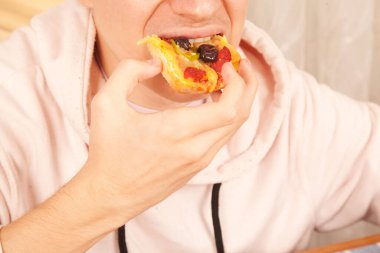 Sakallı, beyaz, pembe tişörtlü olgun bir erkek lezzetli ve harika pizza dilimleri yiyor.