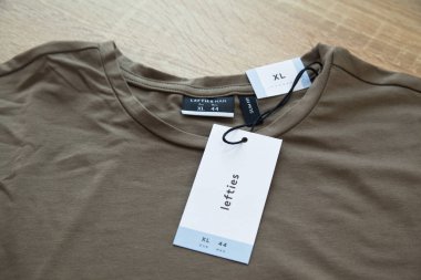 Koyu yeşil Lefties XL yeni tişört ve boş etiket, ahşap zeminde, 29 Mart 2025 İstanbul Maltepe Türkiye Maltepe Solakları mağazası