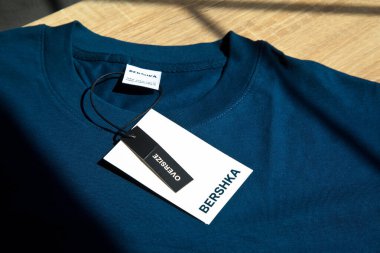 Yeni Blue Bershka L büyük beden tişört ve boş etiket, ahşap zeminde, 29 Mart 2025 İstanbul Maltepe Türkiye Bershka mağazası