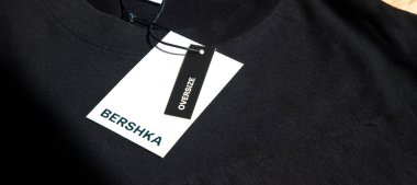 Yeni siyah Bershka L büyük beden tişört ve boş etiket, tahta zeminde, 29 Mart 2025 İstanbul Maltepe Türkiye Bershka mağazası