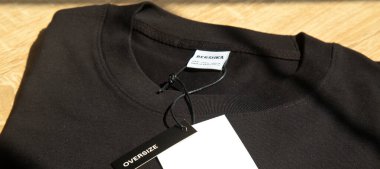 Yeni siyah Bershka L büyük beden tişört ve boş etiket, tahta zeminde, 29 Mart 2025 İstanbul Maltepe Türkiye Bershka mağazası