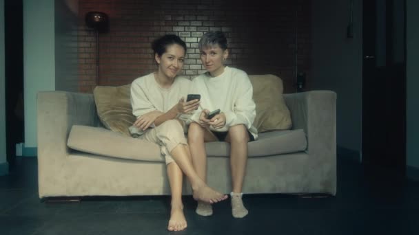 Dos Mujeres Jóvenes Sentadas Con Sus Teléfonos Sofá Casa Cámara — Vídeo de stock