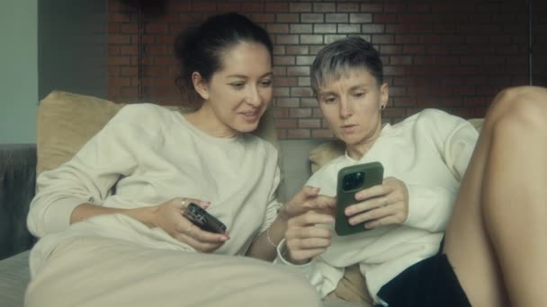 Dos Mujeres Jóvenes Sentadas Con Sus Teléfonos Sofá Casa Cámara — Vídeo de stock