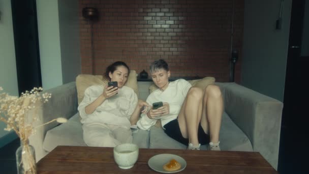 Two Young Women Sitting Phones Couch Home Slow Motion — Stock Video