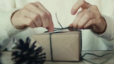 Arkadaşları ve akrabaları için Noel hediyeleri paketleyen genç bir kadın, Noel hediyelerini paketleyen kadınların ellerini kapatın. Noel süsleri, festival sezonuna hazırlanıyor.
