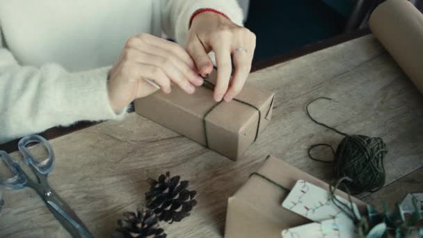 彼女の友人や親戚のためのクリスマスの贈り物を詰め若い女性 クリスマスの贈り物を詰め女性の手の閉じる クリスマスの装飾 お祝いの季節の準備 — ストック動画