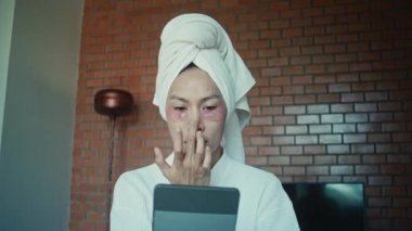 Young asian transgender queer man does his makeup in his room while getting ready for a date
