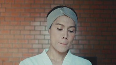 Young asian transgender queer man does his makeup in his room while getting ready for a date