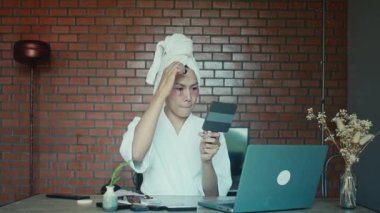 Young asian transgender queer man does his makeup in his room while getting ready for a date