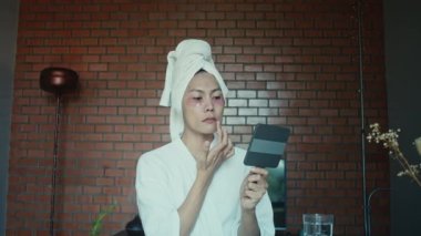 Young asian transgender queer man does his makeup in his room while getting ready for a date