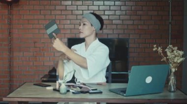 Young Asian transgender queer man learns how to do makeup online on laptop