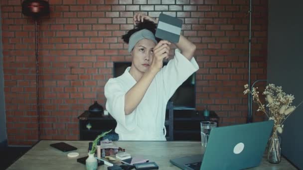若いアジアのトランスジェンダーのクィアの男は ラップトップ上でオンライン化粧を行う方法を学ぶ — ストック動画