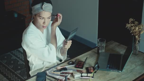 若いアジアのトランスジェンダーの男は化粧をする方法をオンラインで学ぶ — ストック動画