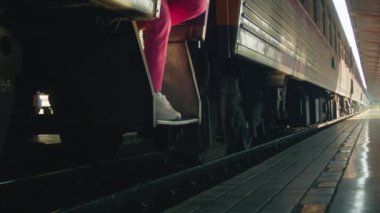 A young woman in a pink suit steps off the train onto the platform and walks to the side, close-up shot in slow motion