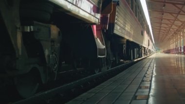 A young woman in a pink suit steps off the train onto the platform and walks to the side, close-up shot in slow motion