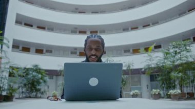 Sokakta dizüstü bilgisayarla çalışan genç bir Afro-Amerikalı iş adamı. Yakışıklı iş adamı portresi, yavaş çekim bmpcc 6k çekim