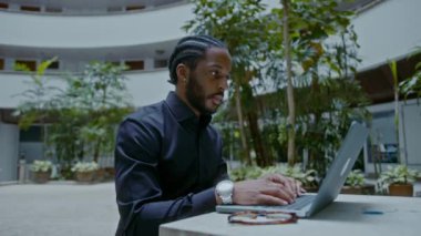 Sokakta dizüstü bilgisayarla çalışan genç bir Afro-Amerikalı iş adamı. Yakışıklı iş adamı portresi, yavaş çekim bmpcc 6k çekim