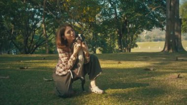 Young woman plays with her Boston Terrier at sunset in park in slow motion