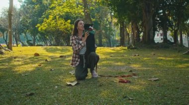 Young woman plays with her Boston Terrier at sunset in park in slow motion