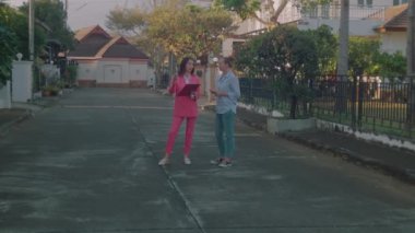 Elinde belgelerle pembe takım elbiseli genç bir emlakçı potansiyel bir müşteriye ev gösteriyor. Yavaş çekim 6k çekim