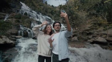 Kuzey Tayland 'da görkemli bir şelalede selfie çeken bir çift. Yüksek kalite 4 km yavaş çekim.