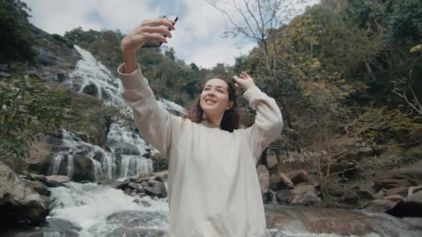 一名年轻女子在泰国北部一座宏伟的瀑布前自拍自拍 慢动作 — 图库视频影像