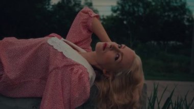 Beton küpün üzerinde uzanmış, eski moda elbiseli bir kadının yakın çekimi. Yüksek kalite ağır çekim 4k görüntü