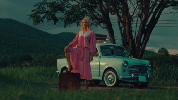 Blondynka Zabytkowej Różowej Sukience Położyła Stopę Walizce Tle Turkusowego Samochodu — Wideo stockowe