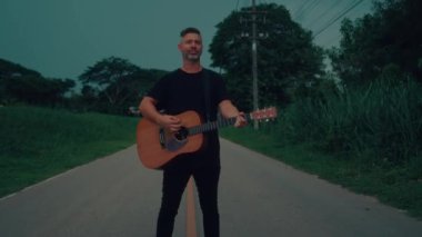 Gitarist yolda çalıp şarkı söylüyor. Yüksek kaliteli el kamerası görüntüsü 4K
