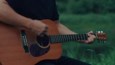 Gitarist göl kenarında çalıyor ve şarkı söylüyor. Yüksek kaliteli el kamerası görüntüsü 4K