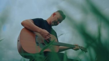 Gitarist göl kenarında çalıyor ve şarkı söylüyor. Yüksek kaliteli el kamerası görüntüsü 4K