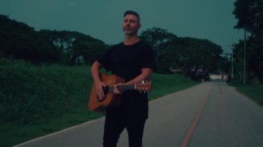Gitarist yolda çalıp şarkı söylüyor. Yüksek kaliteli el kamerası görüntüsü 4K