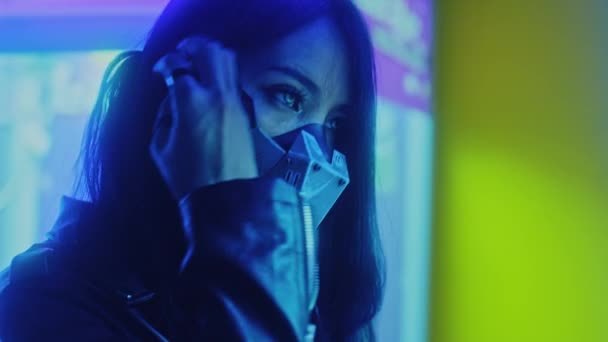 亚洲女人戴着网络朋克面具站在灯光下看着摄像机 慢镜头 高质量的4K镜头 — 图库视频影像