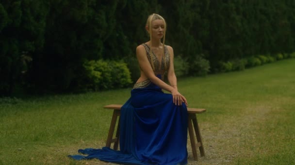 Mulher Glamourosa Luxuoso Vestido Azul Sentado Fundo Beco Com Ciprestes — Vídeo de Stock