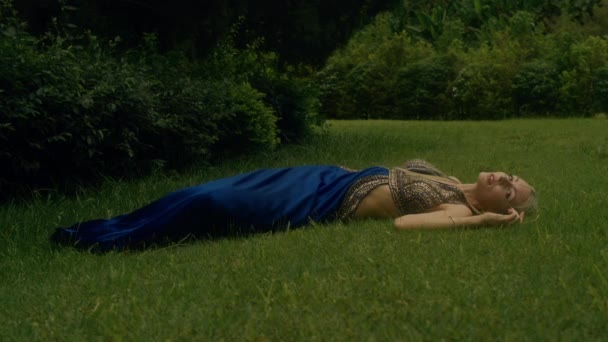 Mulher Glamourosa Luxuoso Vestido Azul Deitado Grama Beco Com Ciprestes — Vídeo de Stock