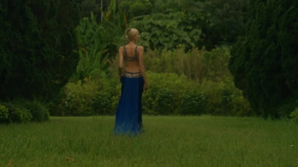 穿着华丽蓝色衣服的有魅力的女人走在一条长满柏树的小巷里 一个优雅的女孩在柏树旁摆姿势 森林里的模型黑魔法6K镜头 — 图库视频影像