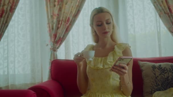 Młoda Blondynka Klasycznej Sukience Rozmawia Przez Telefon Pijąc Herbatę Blackmagic — Wideo stockowe