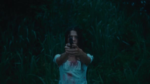 血まみれの服を着た恐ろしい女の子は 彼女の追跡者を狙って 不確実に発砲する彼女の手の銃で立っています ブラックマジック6K映像 — ストック動画