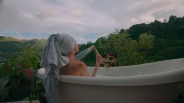 Bir kadın, dağlarda güzel manzaralı, sıcak bir banyo yapar. Kara büyü 6k görüntüsü