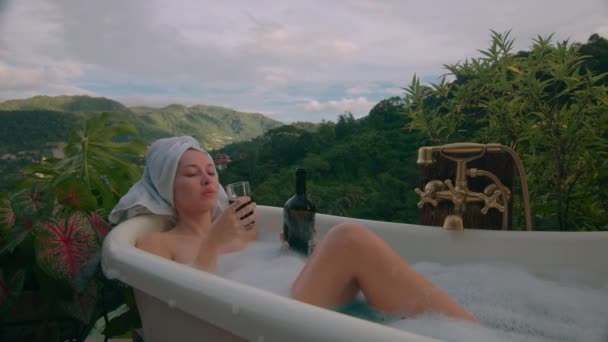 一个女人带着一瓶葡萄酒和美丽的山景正在洗澡 黑魔法6K镜头 — 图库视频影像